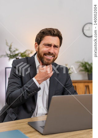 Middle-aged businessman touches throat sharp swallow pain works on laptop seeks relief and care fast 140002004
