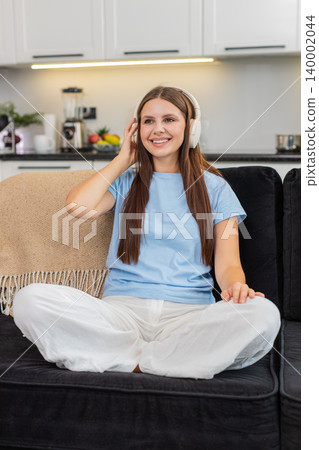 Young woman relaxes with wireless headphones listens to favorite music rests eyes calm and peaceful Young woman relaxes with wireless headphones listens to favorite music rests eyes calm and peaceful 140002044