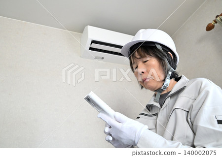 一名女工正在檢查空調機。 一名女工正在檢查空調機。 140002075