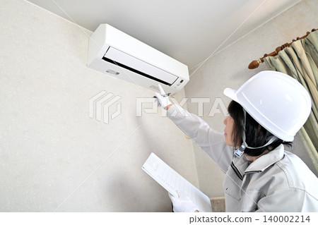 Image of a female worker inspecting an air conditioner. 140002214