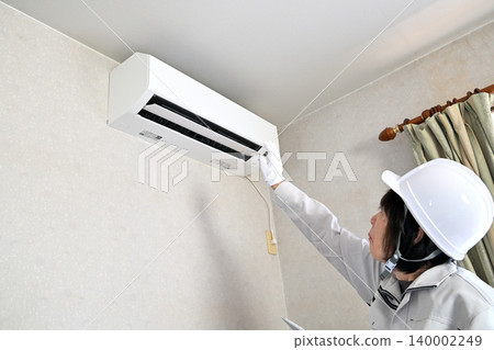 一名女工正在檢查空調機。 一名女工正在檢查空調機。 140002249