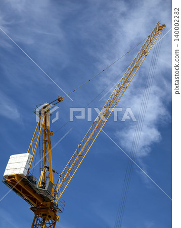 Low angle view of yellow construction crane against blue sky 140002282