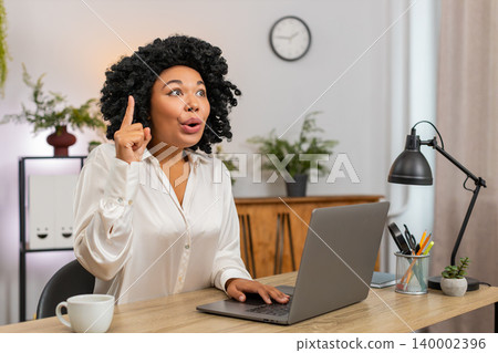 African American businesswoman lifts finger excited Eureka gesture finding solution big idea victory 140002396