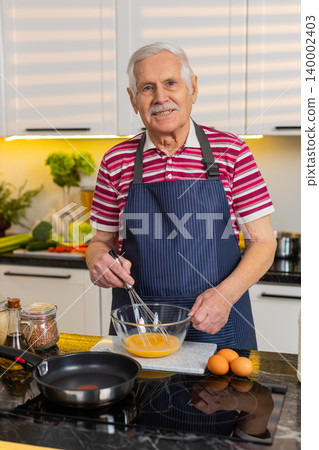 Senior old man whisking eggs for omelet in home kitchen healthy breakfast diet easy cooking routine Senior old man whisking eggs for omelet in home kitchen healthy breakfast diet easy cooking routine 140002403