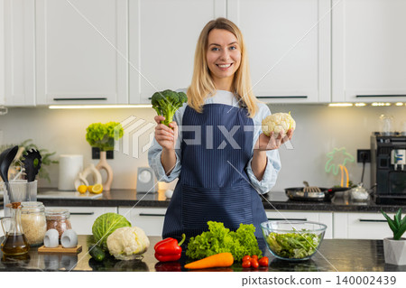Young woman showing broccoli and cauliflower in kitchen promoting keto diet healthy grocery shopping Young woman showing broccoli and cauliflower in kitchen promoting keto diet healthy grocery shopping 140002439