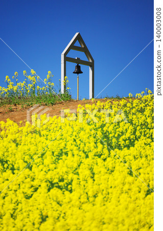 The Bell of Happiness and the fully bloomed rapeseed flowers at the San-no-Kura Plateau flower fields in Kitakata City, Fukushima Prefecture, in a spring scene under a blue sky. The Bell of Happiness and the fully bloomed rapeseed flowers at the San-no-Kura Plateau flower fields in Kitakata City, Fukushima Prefecture, in a spring scene under a blue sky. 140003008