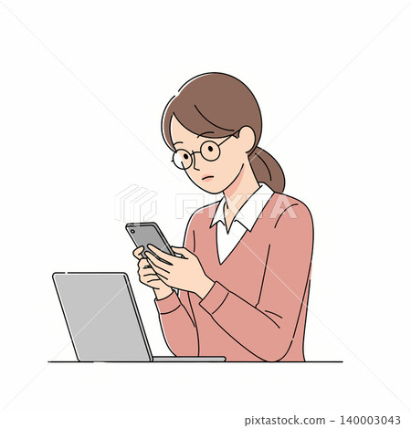 A woman wearing glasses is intently focused on her smartphone while working near a laptop, showcasing modern work life and technology use. 140003043
