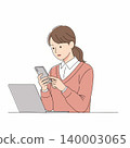 A woman with short brown hair is focused on her smartphone while sitting at a desk with a laptop. She is wearing a pink sweater and a white collared shirt. 140003065