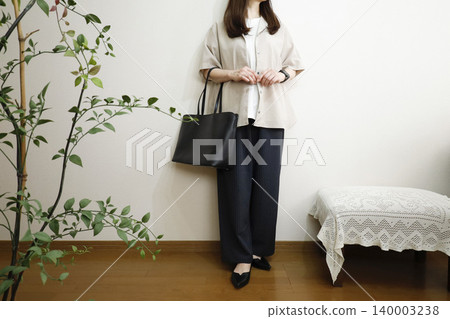 A woman wearing easy pants and a short-sleeved shirt: A summer office casual style image. A woman wearing easy pants and a short-sleeved shirt: A summer office casual style image. 140003238