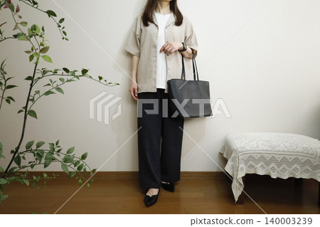 A woman wearing easy pants and a short-sleeved shirt: A summer office casual style image. A woman wearing easy pants and a short-sleeved shirt: A summer office casual style image. 140003239