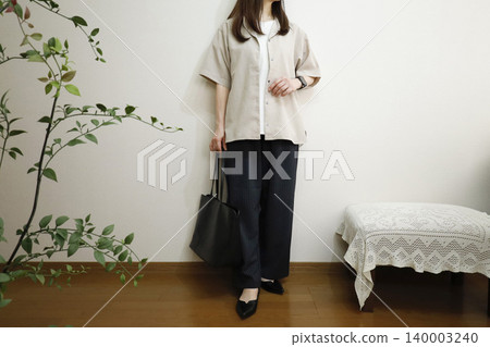 A woman wearing easy pants and a short-sleeved shirt: A summer office casual style image. A woman wearing easy pants and a short-sleeved shirt: A summer office casual style image. 140003240