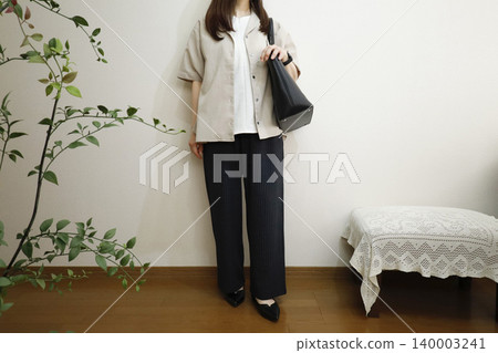 一位女士穿著休閒褲和短袖襯衫：夏季辦公室休閒風格形象。 140003241