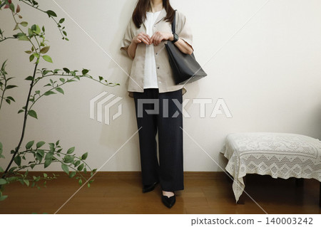 A woman wearing easy pants and a short-sleeved shirt: A summer office casual style image. A woman wearing easy pants and a short-sleeved shirt: A summer office casual style image. 140003242