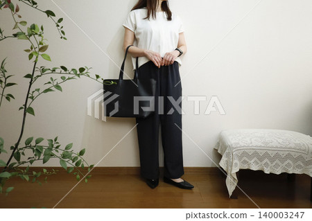 A woman in easy pants for a business outfit; an office casual style that conveys an image of an active worker. A woman in easy pants for a business outfit; an office casual style that conveys an image of an active worker. 140003247