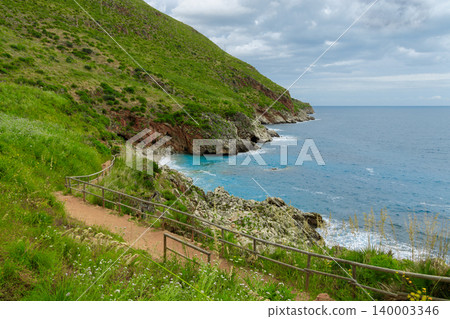 Explore the breathtaking shoreline featuring lush hills and gentle waves along the coast Explore the breathtaking shoreline featuring lush hills and gentle waves along the coast 140003346