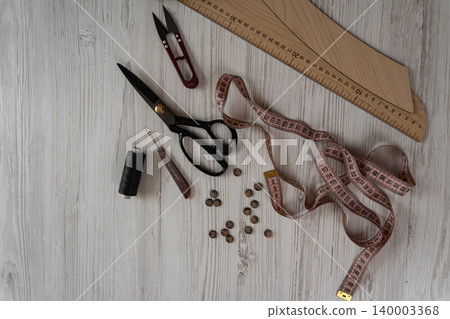 Sewing tools and accessories on table with scissors threads buttons and measuring tape Sewing tools and accessories on table with scissors threads buttons and measuring tape 140003368