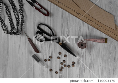 Sewing tools and accessories on table with scissors threads buttons and measuring tape Sewing tools and accessories on table with scissors threads buttons and measuring tape 140003370