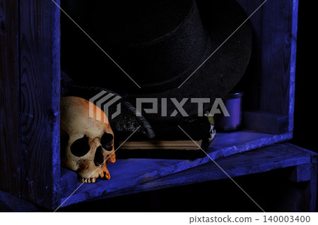 Spooky Halloween still life featuring skull and mysterious book in moody blue lighting Spooky Halloween still life featuring skull and mysterious book in moody blue lighting 140003400