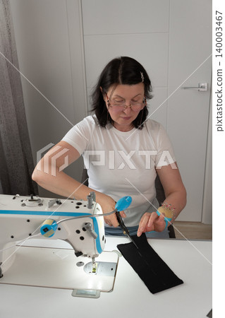 Vertical close up of woman cutting marked fabric for sewing 140003467