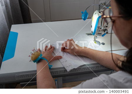 Woman working with fabric and sewing pins in atelier Woman working with fabric and sewing pins in atelier 140003491