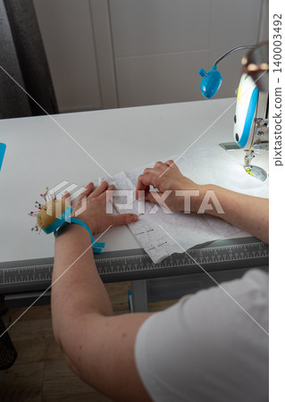 Vertical close up of woman pinning fabric during sewing process Vertical close up of woman pinning fabric during sewing process 140003492