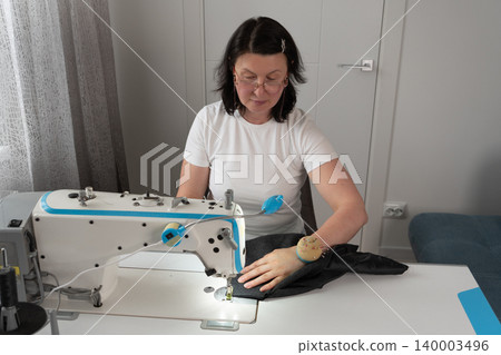 Close up of woman sewing fabric on sewing machine Close up of woman sewing fabric on sewing machine 140003496