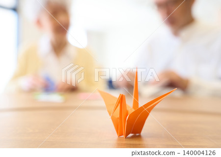 Asian seniors folding origami at a nursing home Asian seniors folding origami at a nursing home 140004126