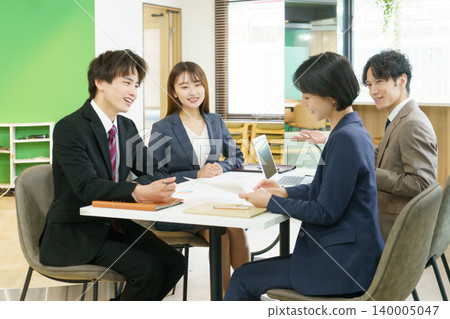 Four young Japanese men and women having a meeting in the office. Four young Japanese men and women having a meeting in the office. 140005047