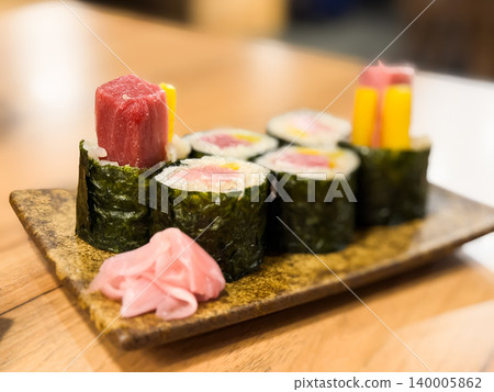 金槍魚腩卷。這是一款捲壽司,內含瘦藍鰭鮪魚和醃蘿蔔,配上粉紅色醃薑。 金槍魚腩卷。這是一款捲壽司,內含瘦藍鰭鮪魚和醃蘿蔔,配上粉紅色醃薑。 140005862