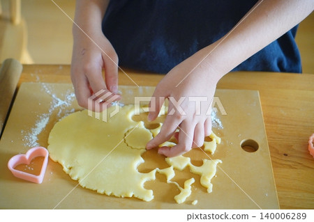 A photo of a child making cookies and cooking at home, using cookie cutters. A photo of a child making cookies and cooking at home, using cookie cutters. 140006289