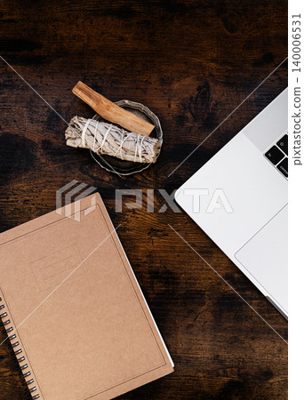 Notebook, laptop and palo santo with white sage on wooden table Notebook, laptop and palo santo with white sage on wooden table 140006531