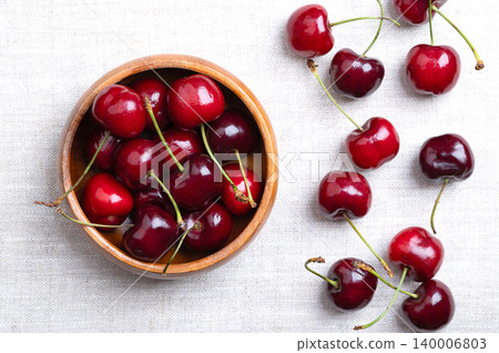 Fresh cherries in a wooden bowl on linen. Ready to eat, red and ripe fruits of the true cherry species Prunus avium, a stone fruit cultivar of the variety Royal Ruby 7. Close-up, from above. Photo Fresh cherries in a wooden bowl on linen. Ready to eat, red and ripe fruits of the true cherry species Prunus avium, a stone fruit cultivar of the variety Royal Ruby 7. Close-up, from above. Photo 140006803