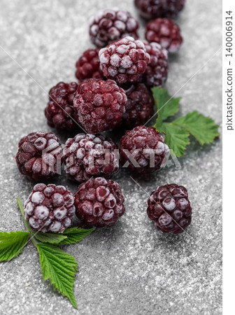 Frozen blackberries with green leaves on gray background 140006914