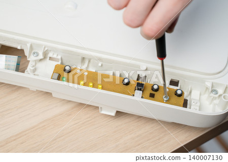 Close-Up Of Hand Using Screwdriver To Repair Electronic Circuit Board Inside All in one Printer Close-Up Of Hand Using Screwdriver To Repair Electronic Circuit Board Inside All in one Printer 140007130