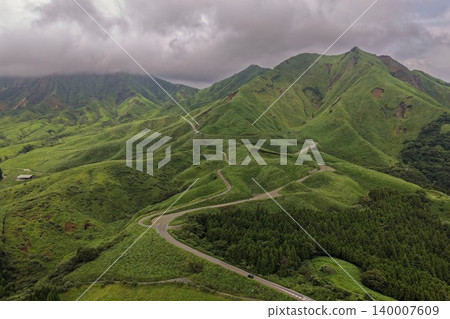 從空中拍攝的照片顯示,一條蜿蜒的道路穿過熊本縣南阿蘇市綠色的山區。 從空中拍攝的照片顯示,一條蜿蜒的道路穿過熊本縣南阿蘇市綠色的山區。 140007609