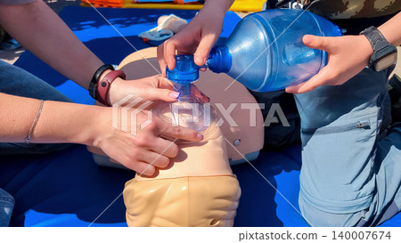 Children learning first aid during cpr training on a medical mannequin. Kids practicing artificial ventilation using an ambu bag resuscitator. 140007674