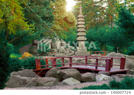 picturesque landscape idyllic natural park outdoor scene spring forest trees green leaves small red bridge and stone terrain with carved religion Asian pillar pilgrimage destination heritage point 140007724