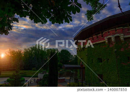 peaceful landmark scenic view garden nature environment space with citadel medieval building in evening sunset time and orange sun light and glare peaceful landmark scenic view garden nature environment space with citadel medieval building in evening sunset time and orange sun light and glare 140007850