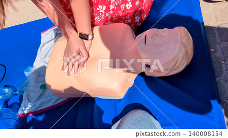First aid training with CPR mannequin. Medical students practicing cardiopulmonary resuscitation and using an Ambu bag mask for artificial ventilation during a first aid seminar. 140008154