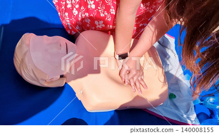 First aid training with CPR mannequin. Medical students practicing cardiopulmonary resuscitation and using an Ambu bag mask for artificial ventilation during a first aid seminar. First aid training with CPR mannequin. Medical students practicing cardiopulmonary resuscitation and using an Ambu bag mask for artificial ventilation during a first aid seminar. 140008155