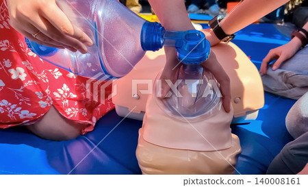 First aid training with CPR mannequin. Medical students practicing cardiopulmonary resuscitation and using an Ambu bag mask for artificial ventilation during a first aid seminar. First aid training with CPR mannequin. Medical students practicing cardiopulmonary resuscitation and using an Ambu bag mask for artificial ventilation during a first aid seminar. 140008161