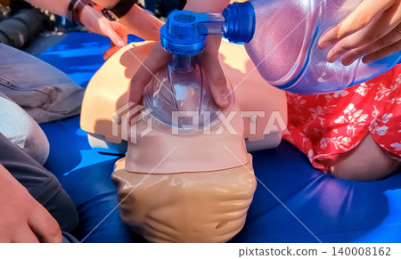 First aid training with CPR mannequin. Medical students practicing cardiopulmonary resuscitation and using an Ambu bag mask for artificial ventilation during a first aid seminar. First aid training with CPR mannequin. Medical students practicing cardiopulmonary resuscitation and using an Ambu bag mask for artificial ventilation during a first aid seminar. 140008162