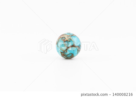 A round bead made of variscite sits alone on a plain white background A round bead made of variscite sits alone on a plain white background 140008216