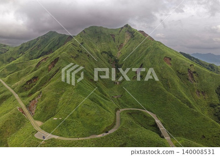 一張空拍照片,展現了熊本縣南阿蘇市綠色的火山山脈和蜿蜒的道路。 一張空拍照片,展現了熊本縣南阿蘇市綠色的火山山脈和蜿蜒的道路。 140008531