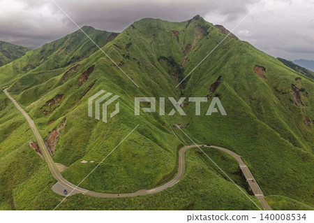 Aerial photograph of a winding mountain road that traverses the lush green slopes of Minami Aso, Kumamoto Prefecture. Aerial photograph of a winding mountain road that traverses the lush green slopes of Minami Aso, Kumamoto Prefecture. 140008534