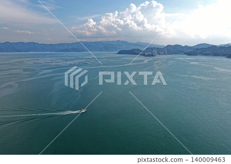 從空中拍攝的照片顯示,一艘船和養殖筏在瀨戶內海佐佐木海岸附近航行,位於大分縣臼杵市。 從空中拍攝的照片顯示,一艘船和養殖筏在瀨戶內海佐佐木海岸附近航行,位於大分縣臼杵市。 140009463