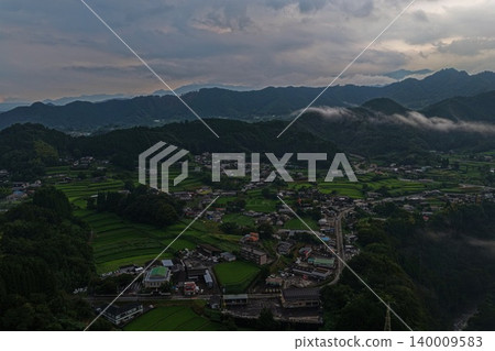An aerial photograph showing terraced rice fields and mountain village settlements in Hinokage Town, Kumamoto Prefecture, viewed from an oblique angle. An aerial photograph showing terraced rice fields and mountain village settlements in Hinokage Town, Kumamoto Prefecture, viewed from an oblique angle. 140009583