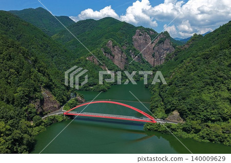 An aerial photograph overlooking the red arch bridge of the Hyugami Dam in Yame City, Fukuoka Prefecture. An aerial photograph overlooking the red arch bridge of the Hyugami Dam in Yame City, Fukuoka Prefecture. 140009629