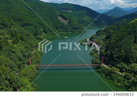 An aerial photograph overlooking the Hyugami Dam Lake and the red suspension bridge in Yame City, Fukuoka Prefecture. An aerial photograph overlooking the Hyugami Dam Lake and the red suspension bridge in Yame City, Fukuoka Prefecture. 140009633