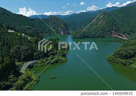An aerial photograph overlooking the Hyugami Dam and red arch bridge in Yame City, Fukuoka Prefecture. An aerial photograph overlooking the Hyugami Dam and red arch bridge in Yame City, Fukuoka Prefecture. 140009635
